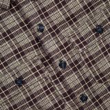 Close-up of the Eaton Cotton Sport Shirt by RALPH LAUREN RRL, featuring a brown and beige plaid cotton twill fabric with black buttons. The checkered pattern evokes a vintage workshirt style, and a clothing tag with the RRL logo is partially visible at the top left corner.