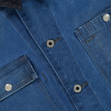 Close-up of the Ellis Cotton Long Sleeve Work Shirt by RALPH LAUREN RRL, featuring blue denim fabric, silver buttons, two chest pockets with visible stitching, and a dark corduroy collar. The texture of the fabric and the details of the pockets and collar are clearly shown.