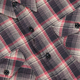 Close-up of the Jasper Cotton Long Sleeve Workshirt by RALPH LAUREN RRL, featuring a relaxed fit with black buttons, chest pockets, and a visible collar. The shirt displays a plaid pattern of red, black, and white stripes and includes a partially visible fabric label near the collar.