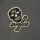 The Jersey Cotton Graphic Short Sleeve T-Shirt from RALPH LAUREN RRL is crafted from black cotton and features a bold motorcycle skull and crossbones patch with “NY Hill Climbers Top” emblazoned across it. The white and gold embroidered patch adds a subtle vintage touch to this standout design.
