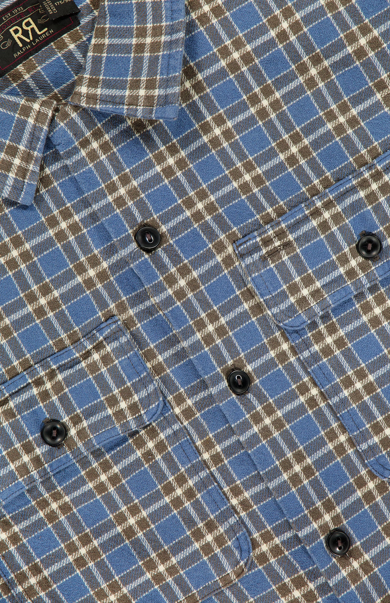 Close-up of the Ralph Lauren RRL Matlock Cotton Long Sleeve Shirt, featuring a blue, brown, and white plaid pattern with two front chest pockets and black buttons. Made from heavyweight cotton twill, this timeless button-up offers a soft, flannel-like texture that evokes vintage appeal.
