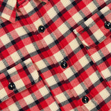 Close-up of the Matlock Plaid Cotton Sport Shirt by RALPH LAUREN RRL, featuring a red, white, and black plaid pattern with black buttons and two chest pockets. Designed in the style of a vintage workshirt, this shirt showcases a partially visible label in the top left corner.