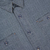 Close-up of the Montgomery Cotton Sport Shirt by RALPH LAUREN RRL, featuring blue textured cotton fabric, two front pockets, visible stitching, and a collar. A black label with gold text is partially visible near the neckline, emphasizing the classic workshirt fit.