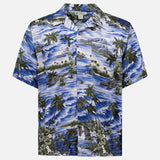 The RALPH LAUREN RRL Rayon 2-Pocket Camp Shirt is a short-sleeved, button-up blue shirt with tropical palm trees, waves, and green foliage motifs printed on lightweight woven fabric.