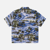 The RALPH LAUREN RRL Rayon 2-Pocket Camp Shirt is a blue, short-sleeve button-up with tropical palm tree and ocean wave motifs, crafted from lightweight woven fabric and shown flat on a white background.