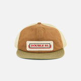 Front view of the Roughout Suede Trucker Cap by RALPH LAUREN RRL in tan and brown suede, featuring a beige mesh back. The front panel displays a rectangular patch with “DOUBLE RL” in red text against a white and brown background, while an adjustable back strap offers a comfortable fit.