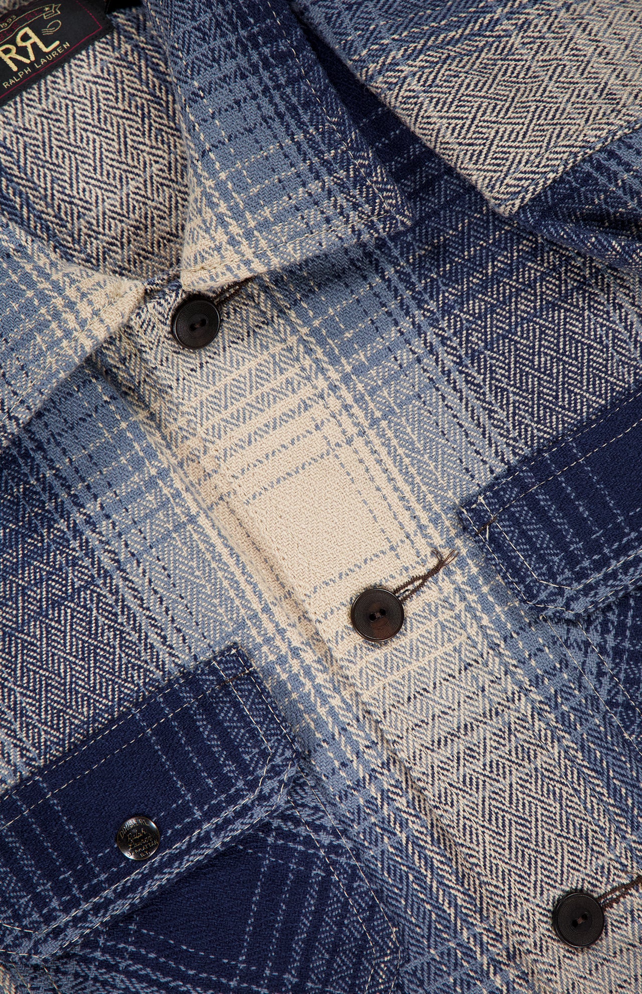 Close-up of the Ruddic Wool Blend Sport Shirt by RALPH LAUREN RRL, featuring a blue shadow-plaid pattern, black buttons, textured woven fabric, and a flap pocket on the left side—perfect as a classic vintage overshirt.