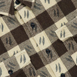 Close-up of a brown and beige plaid Spade Wool Long Sleeve Sportshirt by RALPH LAUREN RRL, featuring black leaf motifs, black buttons, two front pockets, and an RRL tag.