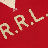 Close-up of the RALPH LAUREN RRL Terry Cotton Graphic Crewneck Sweatshirt, featuring a red hue with cream-colored “R.R.L.” lettering stitched on the front and a cream ribbed collar. Made from soft terry cotton, this pullover also showcases a black label with gold RRL branding near the neckline.