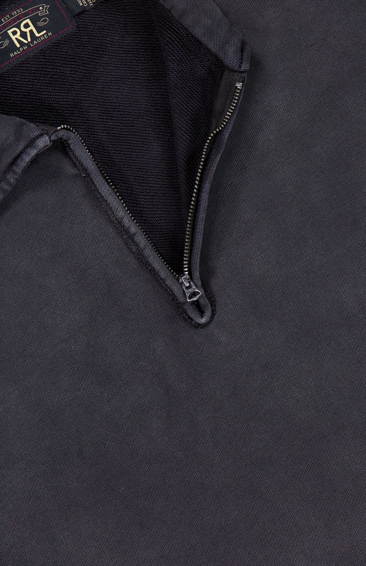 Close-up of the Terry Quarter Zip Pullover Sweatshirt by RALPH LAUREN RRL, featuring a dark fabric with a partially unzipped metal zipper reminiscent of a classic quarter zip design, revealing the inner lining and an RRL Ralph Lauren label in the upper left corner.