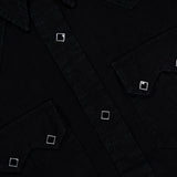 Close-up of the Western Denim Sawtooth Workshirt by RALPH LAUREN RRL, crafted from premium black Japanese denim. The shirt features two chest pockets with sawtooth flaps, silver square buttons, and visible contrast stitching. The collar and part of the RRL label are also visible at the top left.
