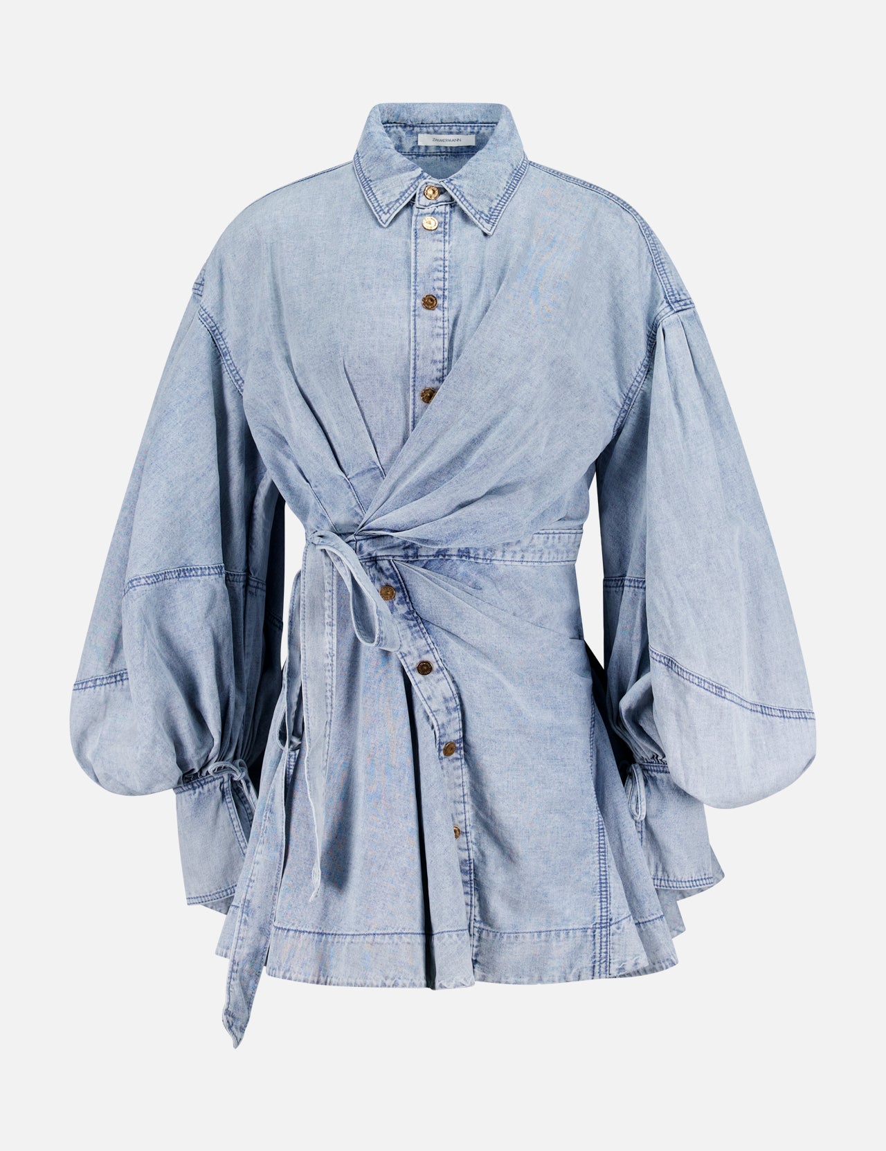 The Rebellion Denim Wrap Mini Dress by ZIMMERMANN features light blue denim, balloon sleeves, a button-down front, pointed collar, self-tie belt wrap silhouette, and a subtly flared hem with visible seam accents.