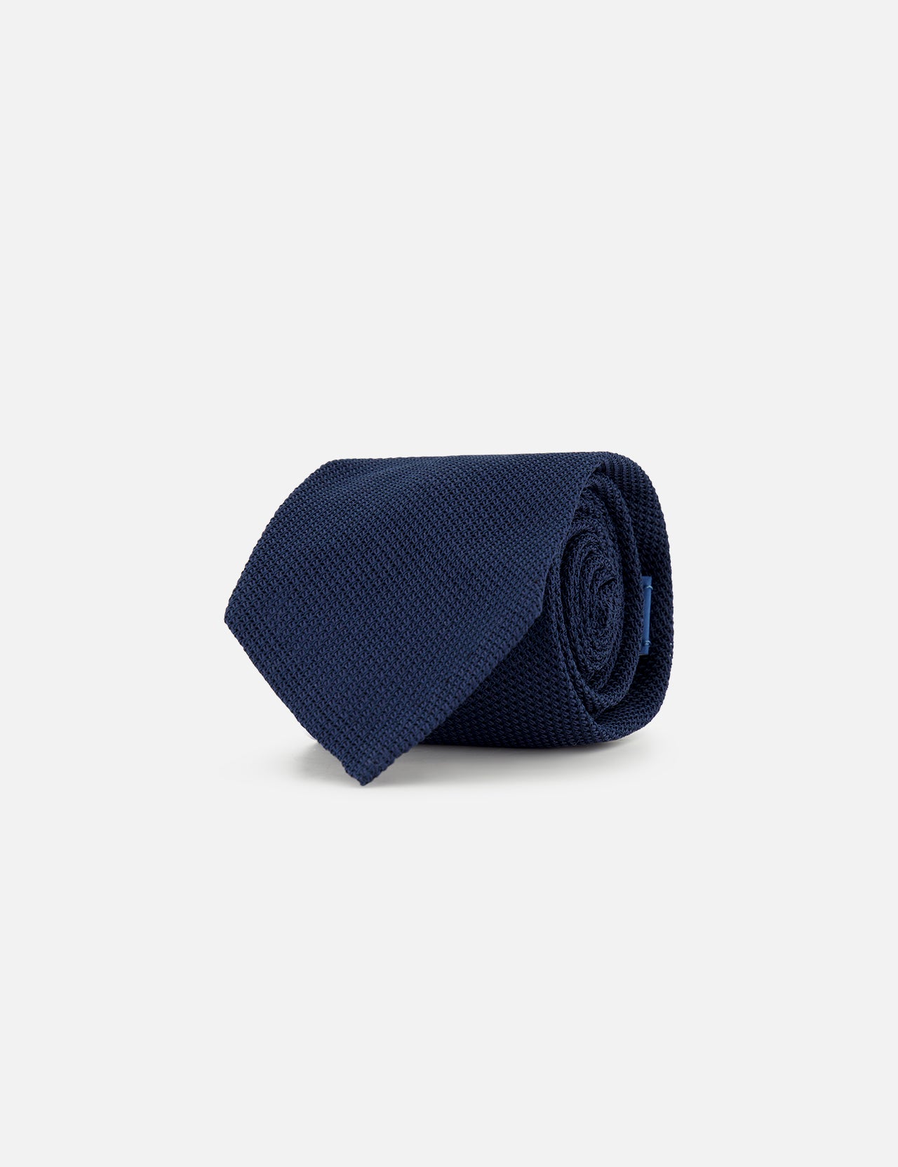 The Duvall Grenadine Unlined Tie by ROBERT TALBOTT in navy blue silk is neatly rolled and displayed on a plain light gray background.