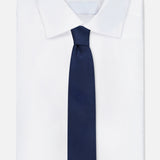 A crisp white dress shirt with a classic collar, featuring the ROBERT TALBOTT Duvall Grenadine Unlined Tie in navy on top, set against a plain white background.