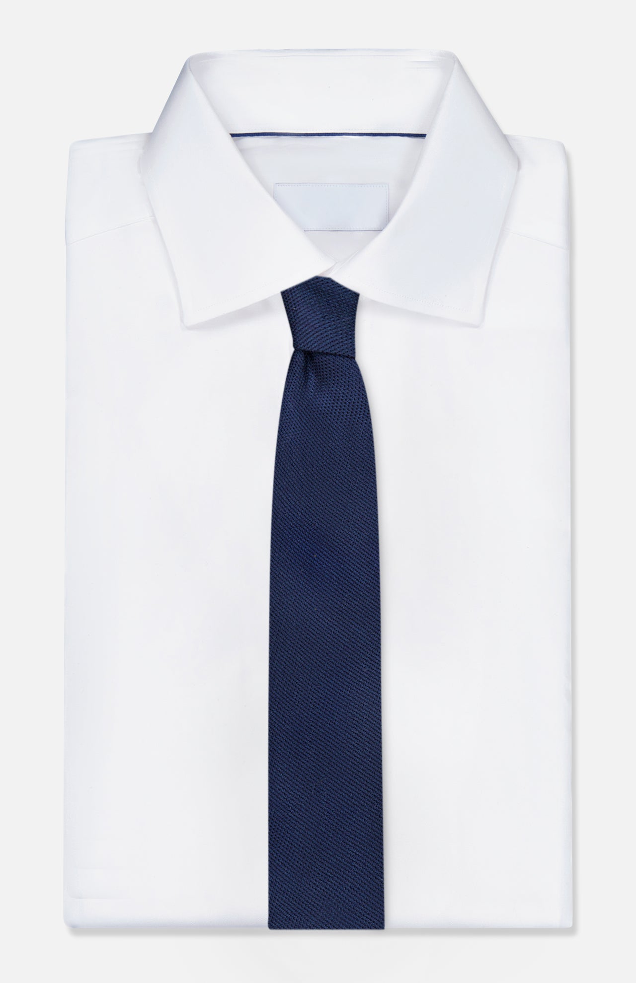 A crisp white dress shirt with a classic collar, featuring the ROBERT TALBOTT Duvall Grenadine Unlined Tie in navy on top, set against a plain white background.
