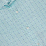 Close-up of the ROBERT TALBOTT Reynolds Windowpane Cotton Linen Dress Shirt, featuring light blue fabric with a fine blue windowpane pattern, white buttons, a collar, and a visible label inside the neckline.