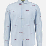The Reynolds Novelty Embroidery Bengal Dress Shirt by ROBERT TALBOTT is a long-sleeve button-up crafted from premium Italian fabric, featuring striking blue and white vertical stripes with distinctive small red “SHIT HAPPENS” embroidery repeated throughout—a statement piece designed for men’s fashion enthusiasts.