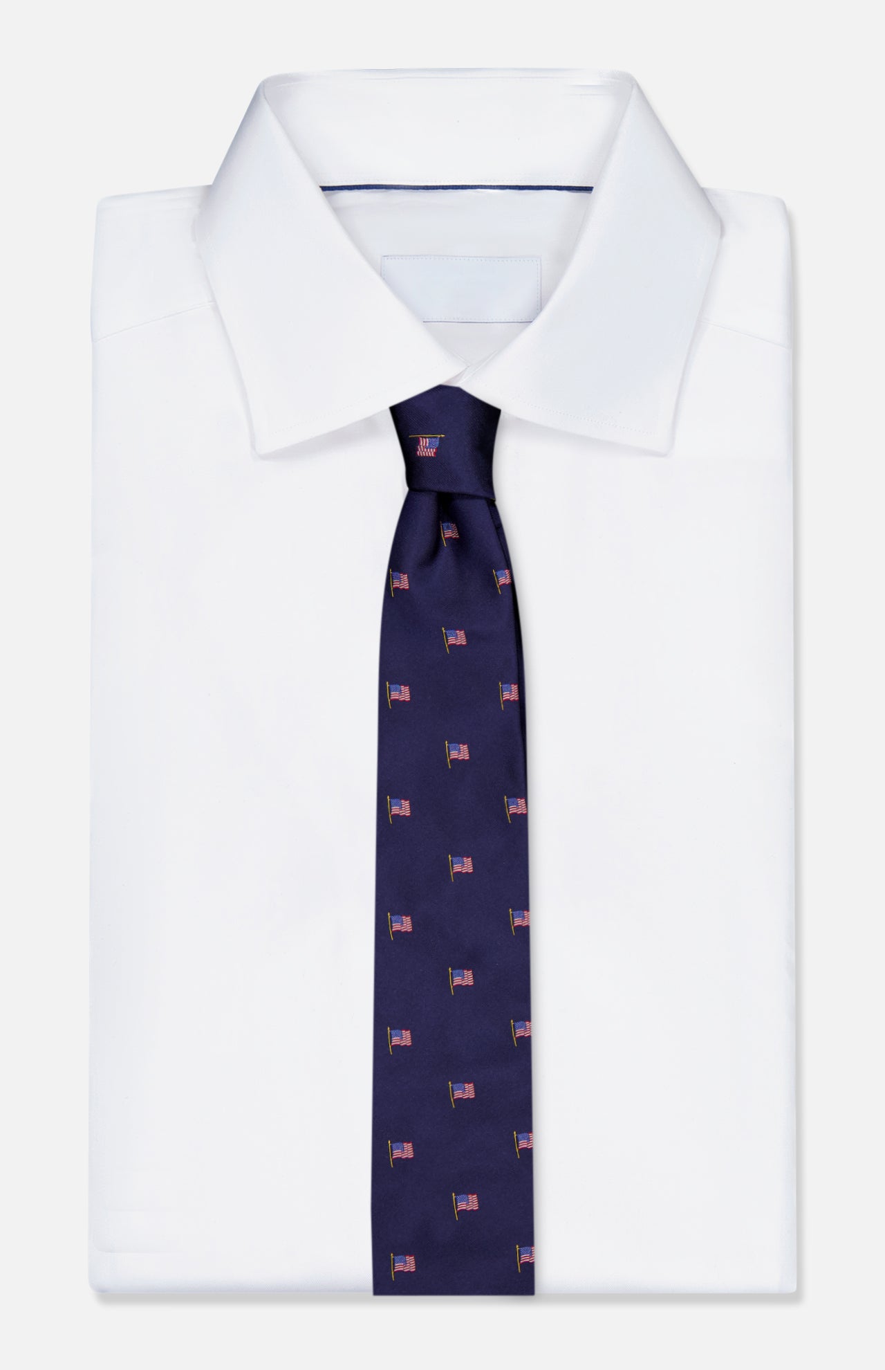 A crisp white dress shirt is shown with the ROBERT TALBOTT Robert American Flag Neck Tie, a navy silk tie featuring a repeating American flag print, set against a plain light background.