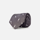 The ROBERT TALBOTT Robert Champagne Glass Tie, in dark grey silk and featuring a subtle pattern of small white champagne glass icons, is shown rolled up on a plain white background.