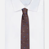 A neatly folded white dress shirt is shown with the ROBERT TALBOTT Robert Fishing Flies Tie—a brown silk accessory adorned with a vibrant fishing lure print—displayed on a plain white background.