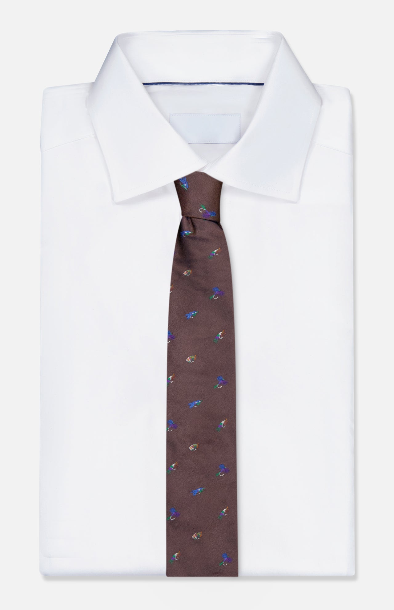 A neatly folded white dress shirt is shown with the ROBERT TALBOTT Robert Fishing Flies Tie—a brown silk accessory adorned with a vibrant fishing lure print—displayed on a plain white background.