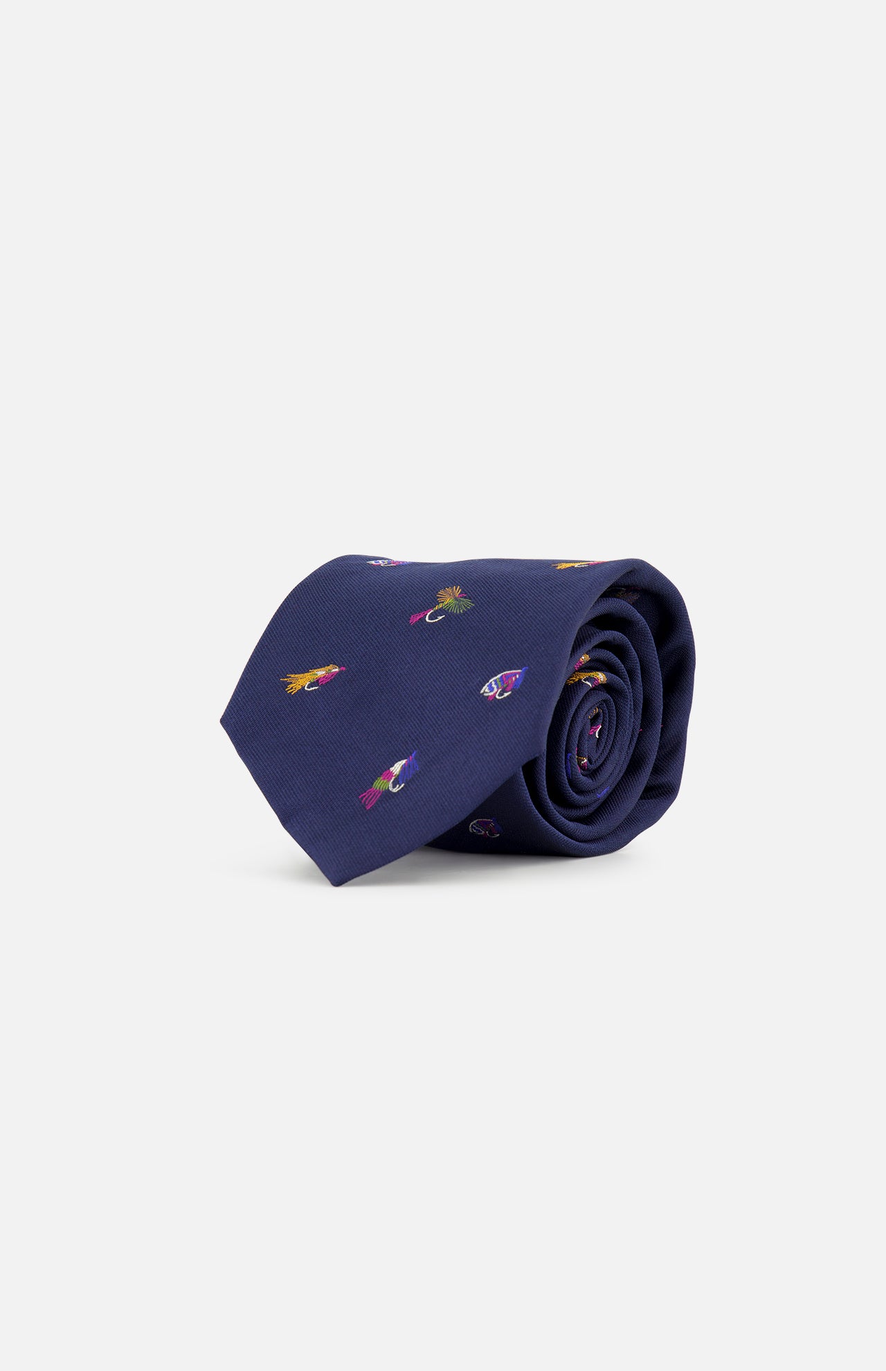 A navy silk tie featuring small, colorful embroidered fishing fly motifs—including playful and vibrant designs—rolled up on a plain white background, the Robert Fishing Flies Tie by ROBERT TALBOTT brings a whimsical twist to classic men’s luxury style.