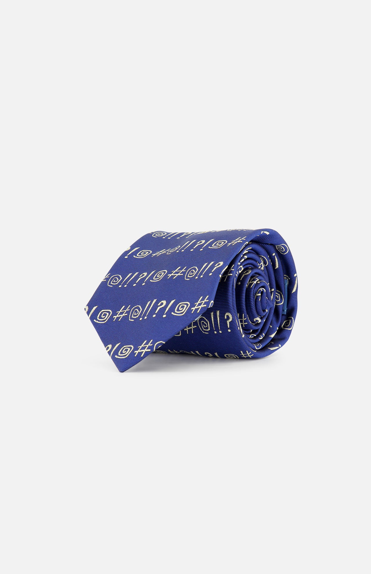 The Robert Grawlix Tie by ROBERT TALBOTT is a luxury blue silk necktie, rolled up and adorned with a repeating grawlix print of white exclamation points, question marks, and spirals, all showcased on a plain white background.