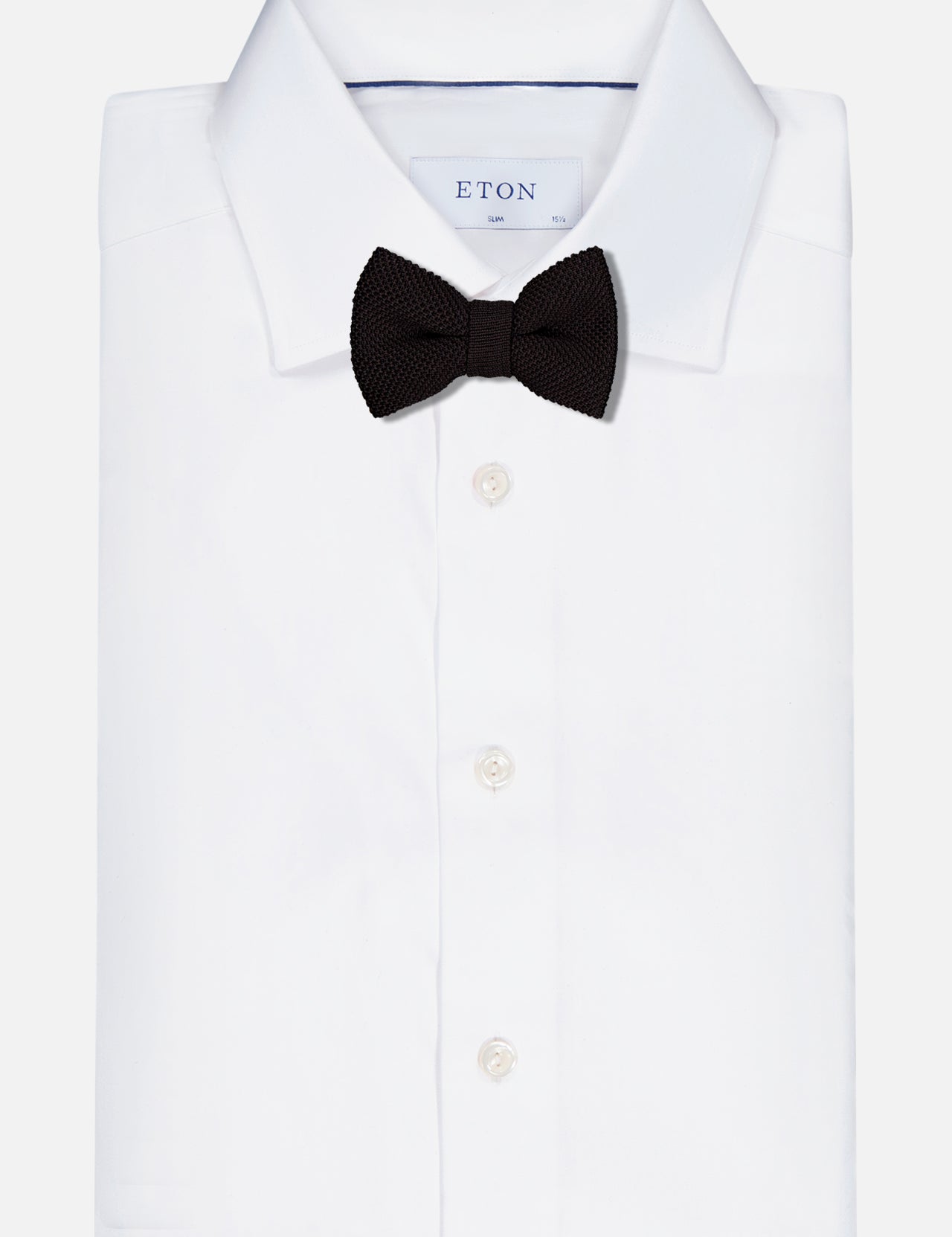 The Ryan Silk Knit Pre-Tied Bow Tie by ROBERT TALBOTT is showcased on a neatly folded white dress shirt, set against a plain background.