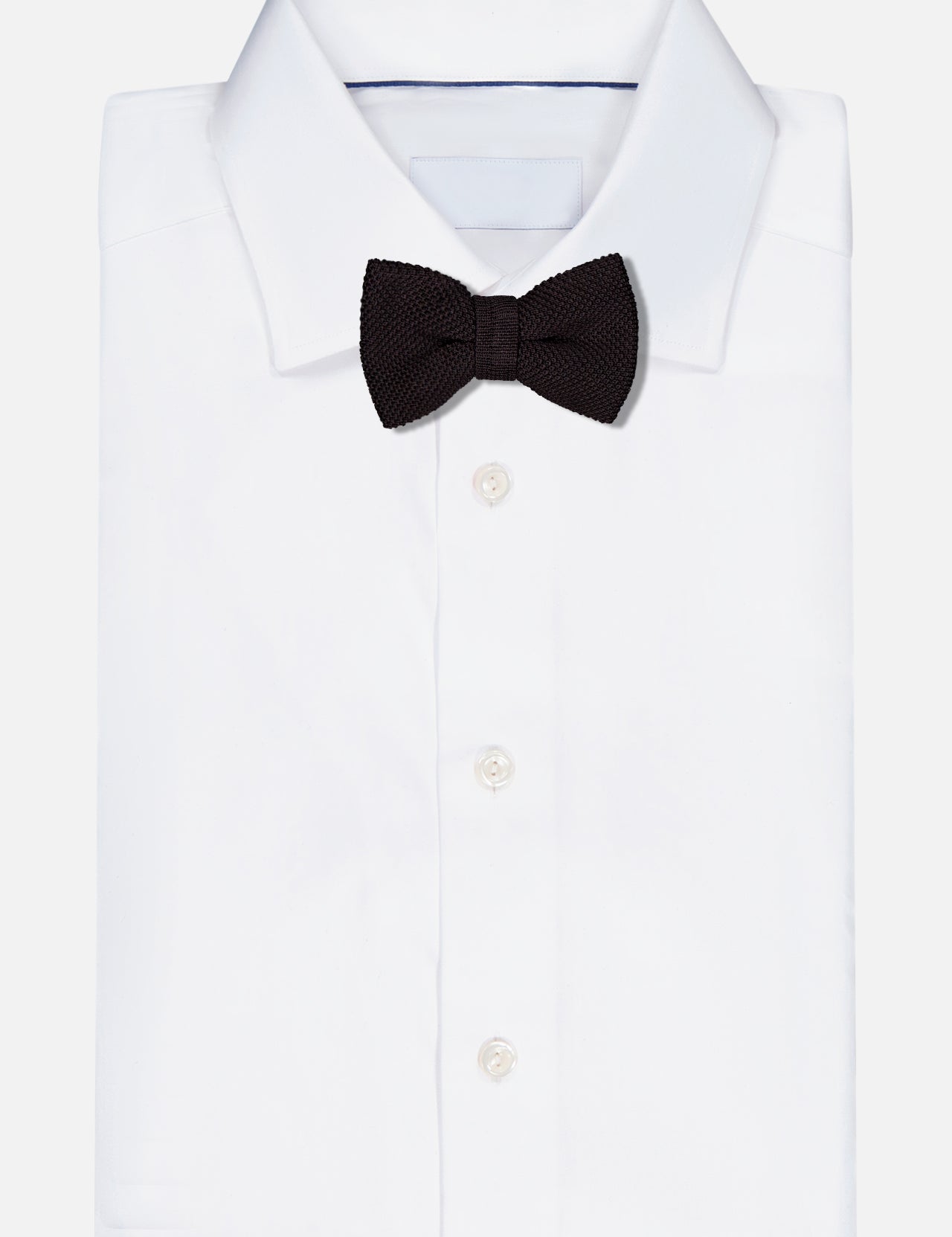 A luxurious ROBERT TALBOTT Ryan Silk Knit Pre-Tied Bow Tie in black, handmade in Italy, is elegantly displayed on a neatly folded white dress shirt against a plain white background.