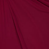 A close-up of deep red fabric with soft folds and drapes, echoing the elegant lines and shadows of the Anya Ruched Maxi Dress by RONNY KOBO.