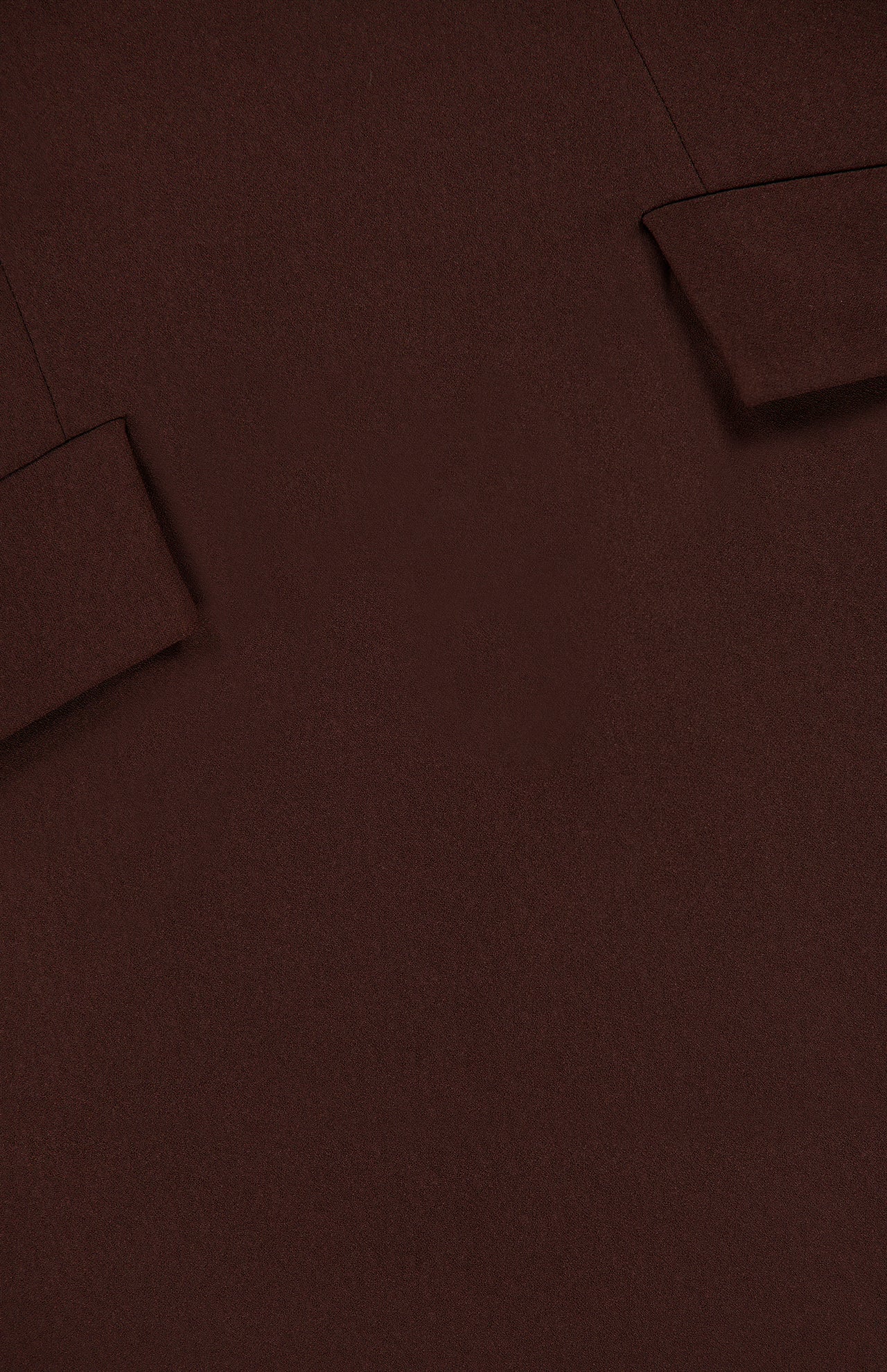 Close-up of the Brette Pocket Mini Dress by RONNY KOBO in chocolate brown fabric, featuring two angled, rectangular flaps stitched at the top corners—details that hint at tailored, jacket-inspired design elements.