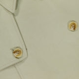 Close-up of the Cohen Oversized Raincoat by RONNY KOBO in light beige, featuring a trenchcoat-inspired collar, lapel, and four tan buttons with stitched details.