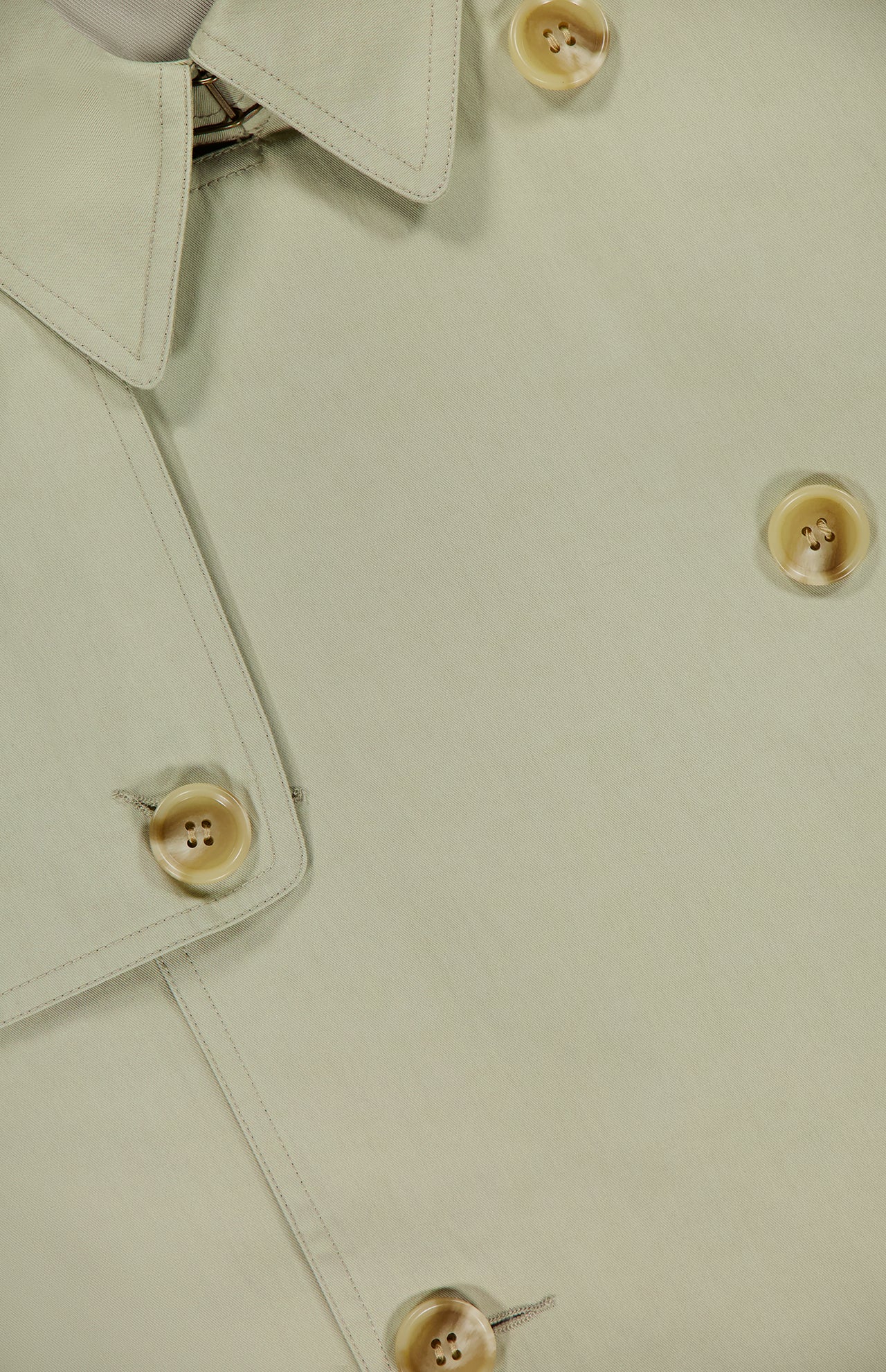 Close-up of the Cohen Oversized Raincoat by RONNY KOBO in light beige, featuring a trenchcoat-inspired collar, lapel, and four tan buttons with stitched details.