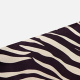 A section of the Feyre Animal Print Skirt by RONNY KOBO, showcasing bold zebra-inspired black and white stripes, is displayed diagonally on a plain white background.