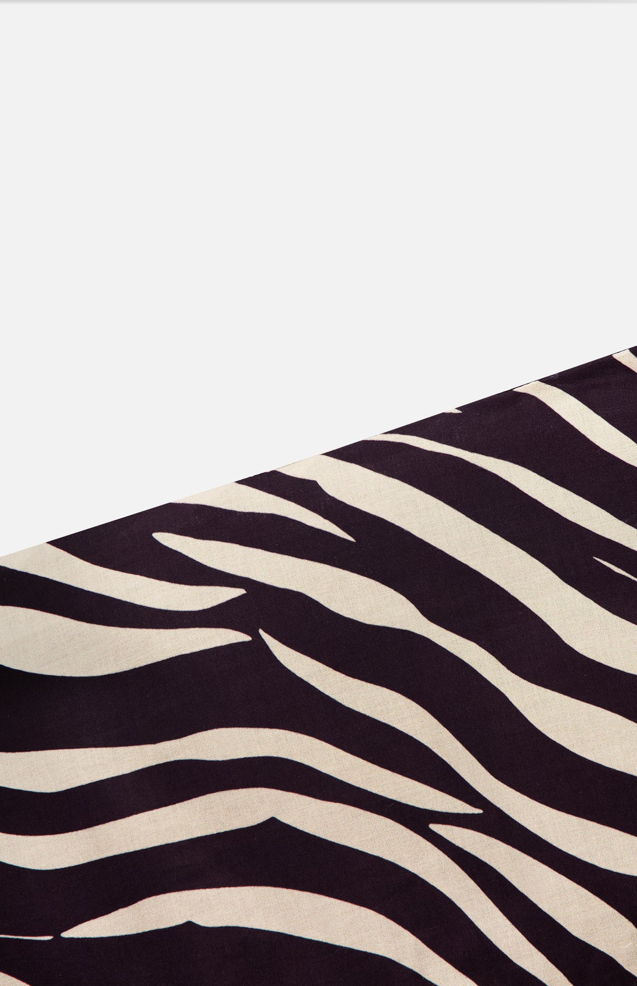 A section of the Feyre Animal Print Skirt by RONNY KOBO, showcasing bold zebra-inspired black and white stripes, is displayed diagonally on a plain white background.