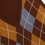 Close-up of the Gabriel Argyle Knit Vest by RONNY KOBO, showcasing a brown knit fabric with an argyle pattern in mustard and gray tones intersected by white lines. The vest features a V-neckline and ribbed edges for a timeless look, with a branded clothing label sewn onto the inner collar.