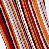 A close-up of the RONNY KOBO Kerry Knit Midi Dress, showcasing ribbed knit fabric with wavy vertical stripes in sunset hues—red, orange, brown, pink, and white—set against a plain white background.