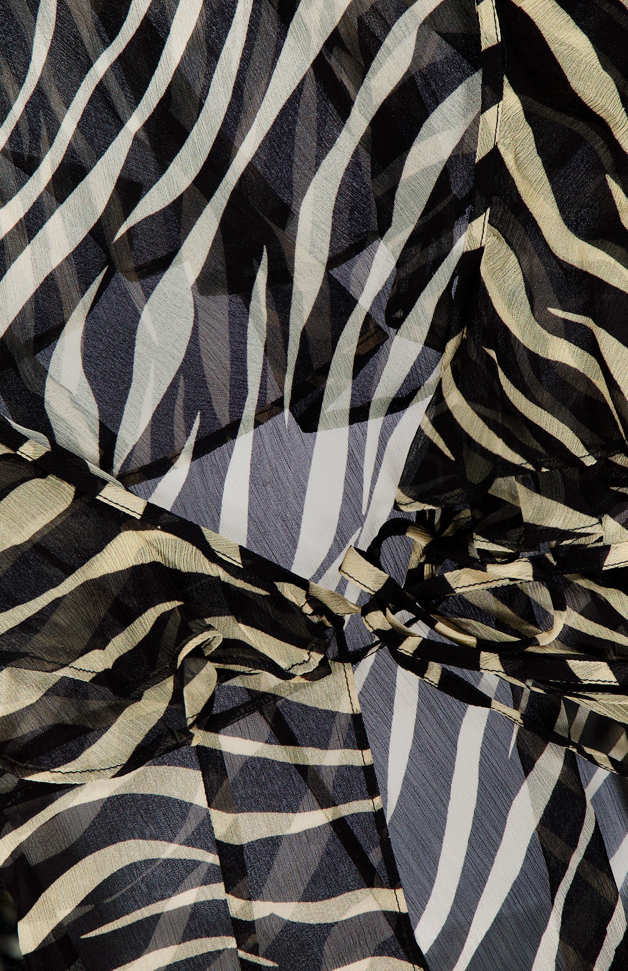 Close-up of the RONNY KOBO Kyle Zebra Print Maxi Top, featuring sheer fabric with striking black and white zebra stripes, arranged in gentle folds and layers for a textured and abstract look.