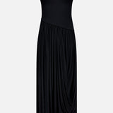 The Meyer Draped Hemline Dress by RONNY KOBO is a minimalist black dress with a sleeveless fitted bodice, racerback, and asymmetrical draped skirt. Shown on a plain white background for an elegant, flowy look.