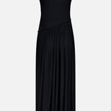 The Meyer Draped Hemline Dress by RONNY KOBO is a sleeveless black dress featuring a fitted racerback top and an asymmetrical pleated skirt with a high-low hem, set against a plain light backdrop.