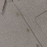 Close-up of the Niall Stripe Pocket Top by RONNY KOBO in grey, highlighting its pinstriped button-up design with a collar, three buttons, a pocket, and part of the label. The subtle vertical stripe pattern on the fabric makes this striped button-down blouse an ideal choice for versatile workwear.