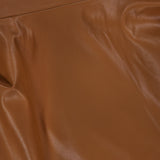 Close-up of the Pelle Faux Leather Mini Dress by RONNY KOBO, featuring smooth, dark brown faux leather fabric with gentle folds and subtle creases that reflect light, highlighting its texture and sheen.