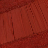 Close-up of the RONNY KOBO Rune Lace Panel Maxi Dress in rust, showcasing pleated fabric and horizontal lace panels for a textured, layered look inspired by bohemian style.
