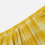 Close-up of the Ryker Plaid Balloon Pant by RONNY KOBO, showcasing its yellow plaid fabric with a gathered, elastic waistband. The pattern features thin blue and white lines against a vibrant yellow background, giving these trendy women's pants an eye-catching and stylish appeal. The lightweight, subtly textured material is perfect for relaxed pull-on styling that blends comfort with modern flair.