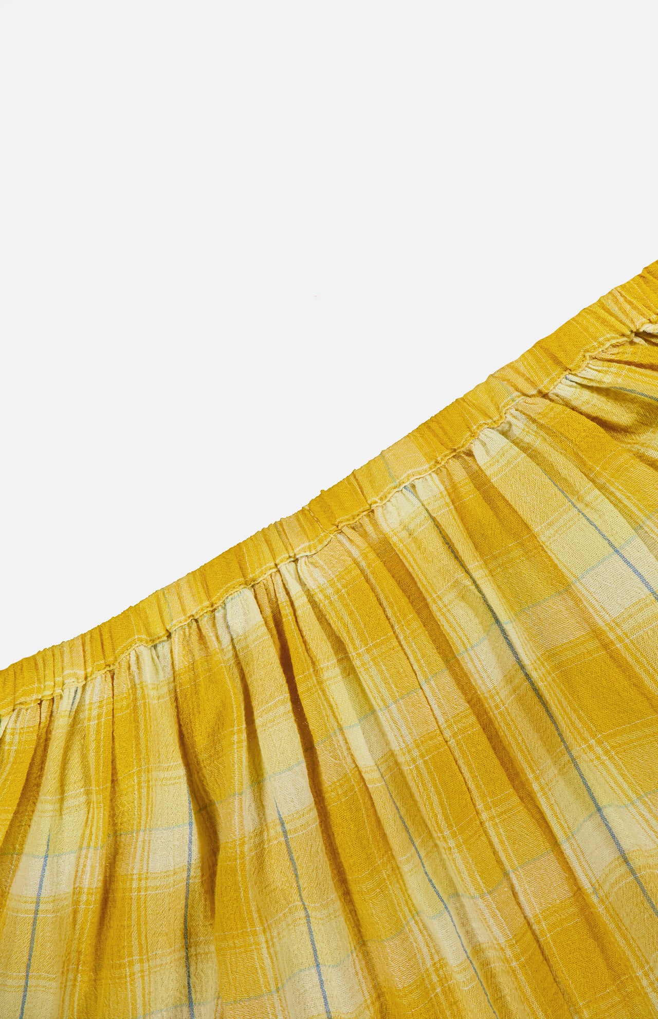 Close-up of the Ryker Plaid Balloon Pant by RONNY KOBO, showcasing its yellow plaid fabric with a gathered, elastic waistband. The pattern features thin blue and white lines against a vibrant yellow background, giving these trendy women's pants an eye-catching and stylish appeal. The lightweight, subtly textured material is perfect for relaxed pull-on styling that blends comfort with modern flair.