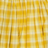 Close-up of yellow plaid fabric featuring white and subtle blue stripes, gathered at the top with pleats—a stylish detail from the Ryker Plaid Balloon Pant by RONNY KOBO.