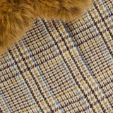 A close-up of brown faux fur resting atop a plaid fabric, woven with beige, brown, blue, and yellow threads in a checkered pattern—details that beautifully enhance the classic style of the RONNY KOBO Savannah Removable Collar Jacket.