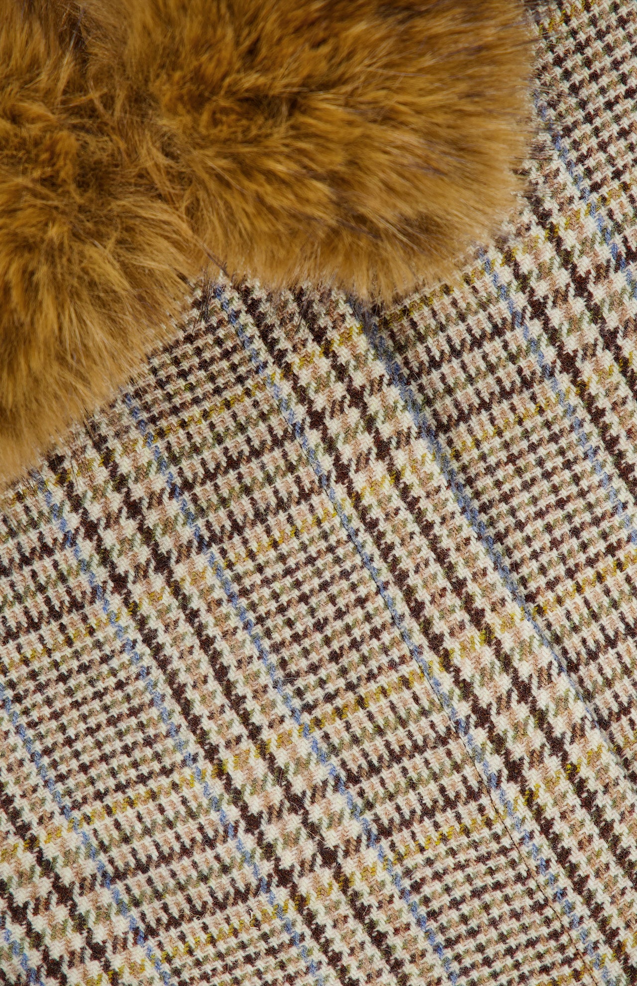 A close-up of brown faux fur resting atop a plaid fabric, woven with beige, brown, blue, and yellow threads in a checkered pattern—details that beautifully enhance the classic style of the RONNY KOBO Savannah Removable Collar Jacket.