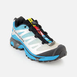 The SALOMON XT-4 OG Sneaker is displayed at an angle on a plain white background, showcasing its blue, white, and black colorway, signature quick-lace system, rugged outsole tread, EnergyCell midsole cushioning, and branded detailing on the side—making it an excellent option for those looking for high-performance trail running shoes engineered for outdoor adventures.