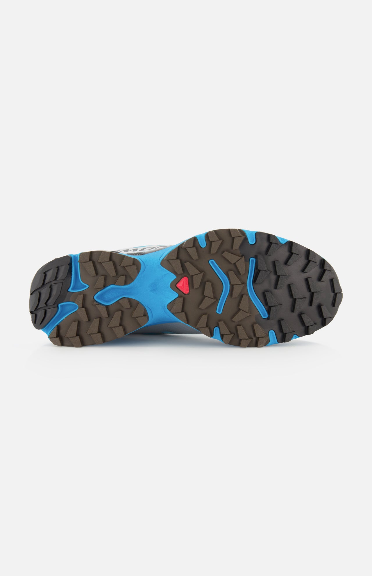 The image shows the bottom of a blue and brown SALOMON XT-4 OG Sneaker, featuring a rugged, textured outsole engineered for stability and grip, with a small red triangular detail near the center—distinctive elements of this performance footwear designed for traction.